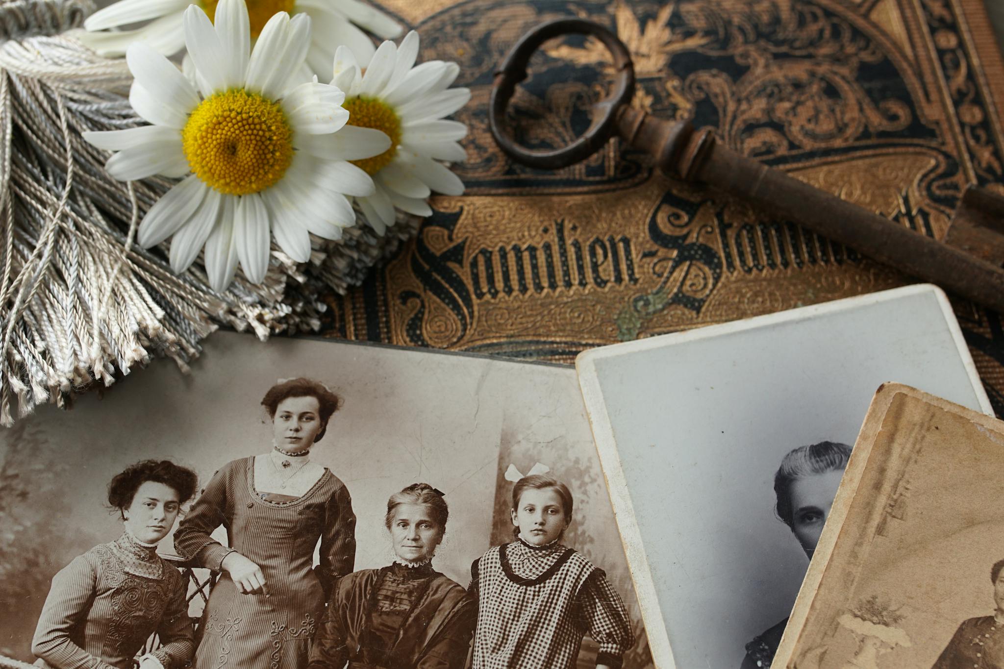 Vintage family photographs with daisies and an antique key evoke memories and nostalgia.